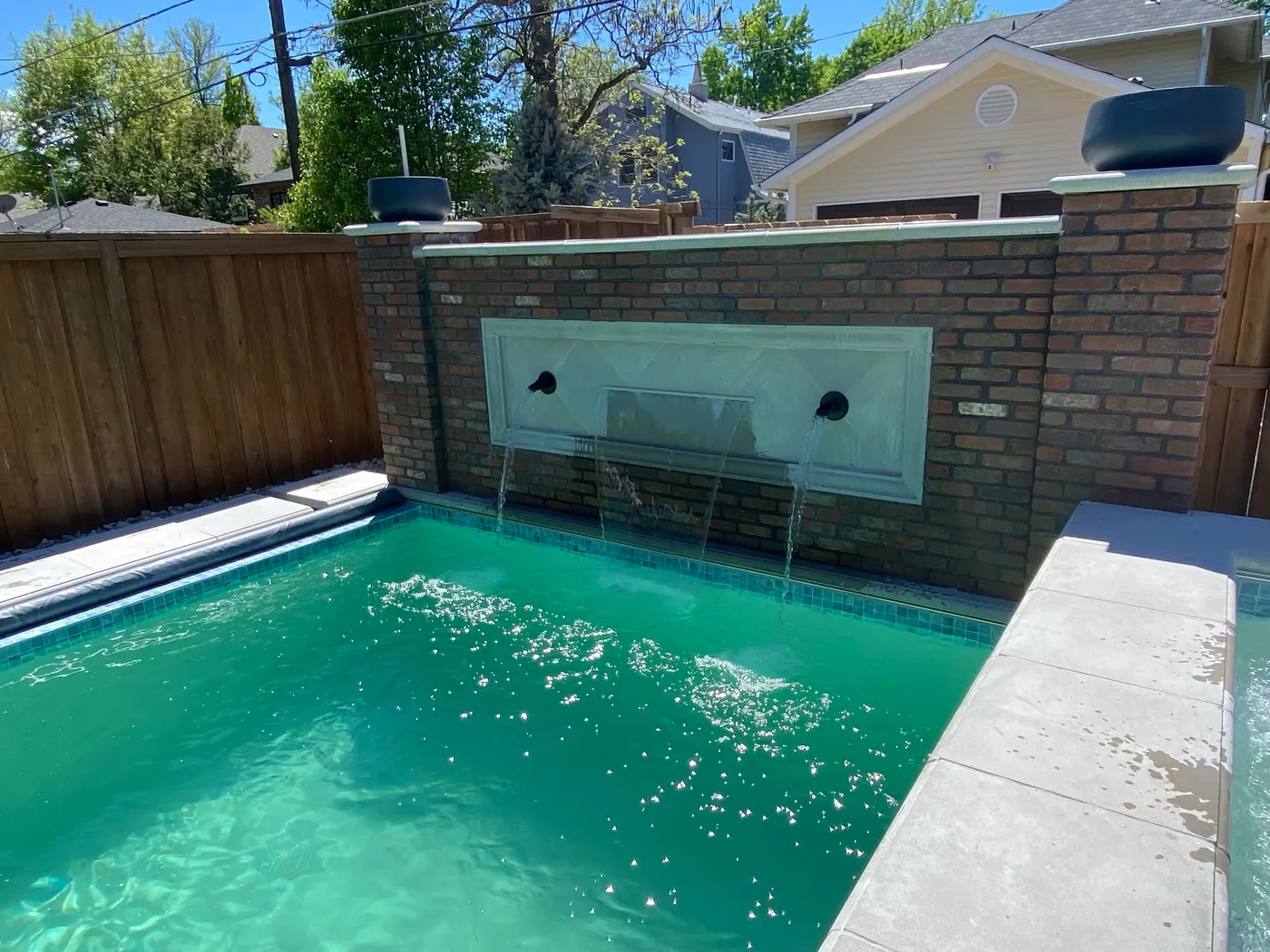 Water wall spilling from a brick garden wall into the water below