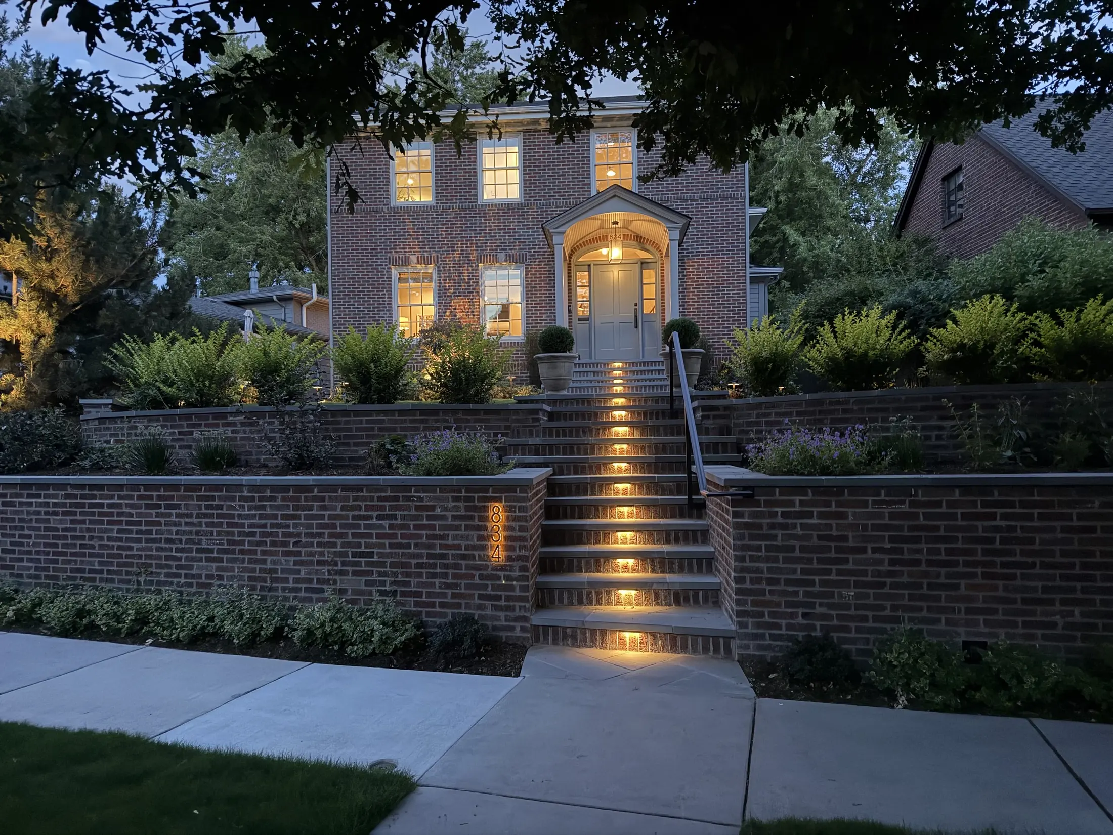 Illuminated garden steps leading to a lit entry at dusk
